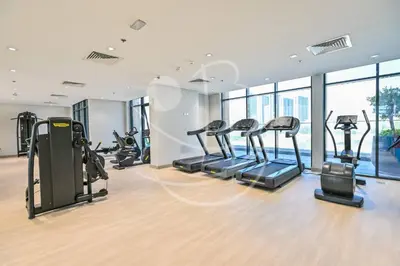 a gym with several treadmills and elliptical machines at Modern Cozy 1BR Retreat Azizi Riviera Dubai in Dubai