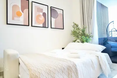a bedroom with a white bed with four pictures on the wall at Private jacuzzi Canal View Infinity Pool in Dubai