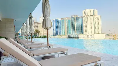 a row of lounge chairs and umbrellas next to a pool at Private jacuzzi Canal View Infinity Pool in Dubai