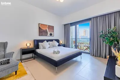 a bedroom with a king sized bed and a balcony at bnbmehomes - Act One Tower in Dubai