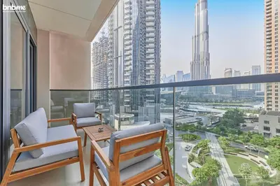 a balcony with two chairs and a table and a large window at bnbmehomes - Act One Tower in Dubai