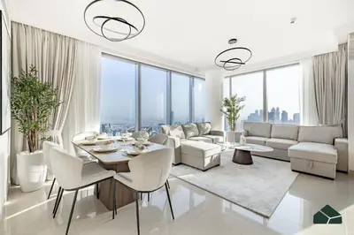 a living room with white furniture and large windows at High Floor 2BR with Full Burj View by BMS in Dubai