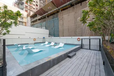 a swimming pool with white chairs in a building at Lux & New 2 BHK in Jumeirah Village Circle I Close to everything I Pool I High Speed Internet I Balcony in Dubai