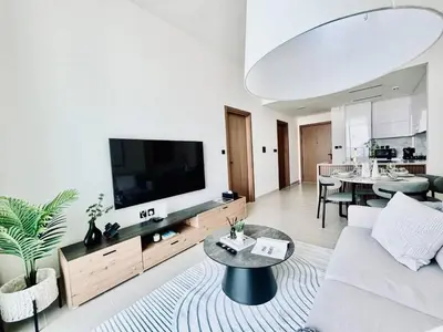 a living room with a couch and a flat screen tv at Soft Modernity 1br Haven With Parking, Gym & Pool! in Dubai