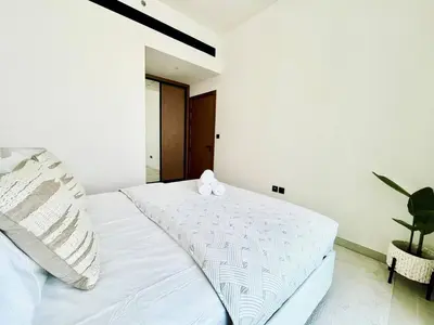 a bedroom with a white bed with two pillows at Soft Modernity 1br Haven With Parking, Gym & Pool! in Dubai