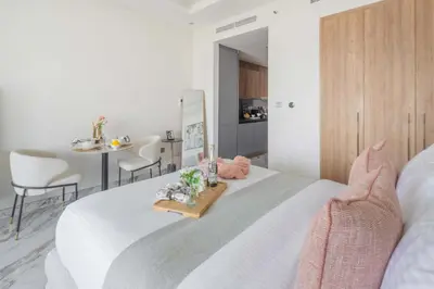 a bedroom with a white bed with a table and chairs at Frank Porter - Taraf 2 Residence in Dubai
