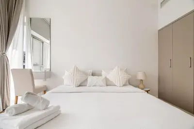 a white bedroom with a large white bed with white pillows at New! 1BR with Balcony Views and Pool by Burj Khalifa in Dubai