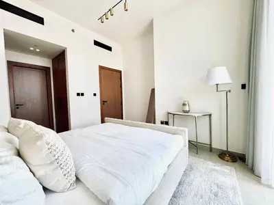 a white bedroom with a white bed and a table at Sun Deck & Sleek Lap Pool Free Gym And Parking! in Dubai