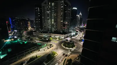 a city skyline at night with cars on a street at Eden Retreat Partition room For Couple In Barsha Heights in Dubai