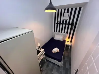 a small room with a chair and a refrigerator at Eden Retreat Partition room For Couple In Barsha Heights in Dubai