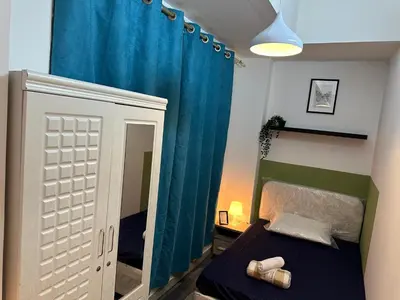 a bedroom with a bed and a blue curtain at Enchanted Stay Partition Room in Barsha Heights in Tecom in Dubai