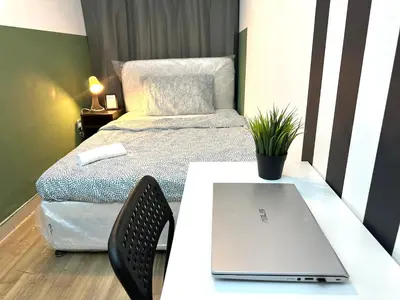 a room with a bed and a laptop on a table at Passion Nest Room in Barsha Heights Tecom in Dubai