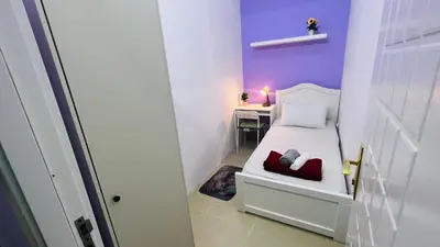 a small bedroom with a white bed and a desk at Solo Haven Room in Barsha Heights Tecom in Dubai