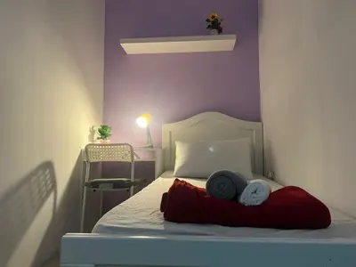 a bedroom with a bed with a red blanket and purple walls at Solo Haven Room in Barsha Heights Tecom in Dubai