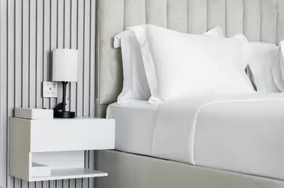 a white bed with a lamp on a side table at Luxury Oasis | Private Beach & Infinity Pool in Dubai