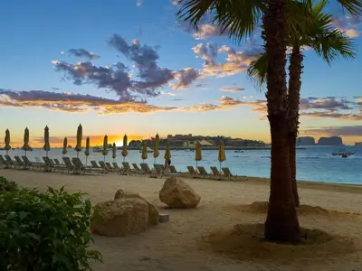 a beach with chairs and umbrellas and a palm tree at Ultra Luxury Apt | Private Beach + Infinity Pool in Dubai