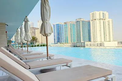 a row of lounge chairs with umbrellas next to a pool at Exclusive Jacuzzi Canal View in Dubai