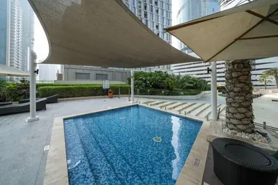 a large swimming pool with a large umbrella at Chic Waterfront 1 Bed with Panoramic Marina Views in Dubai