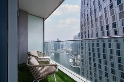 a balcony with two chairs and a view of the water at Chic Waterfront 1 Bed with Panoramic Marina Views in Dubai
