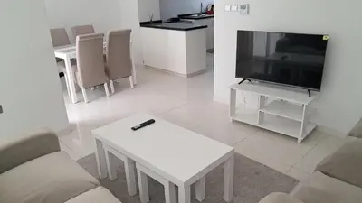 a living room with a tv and a white table at Damac hills 2 vardon cluster townhouse in Dubai