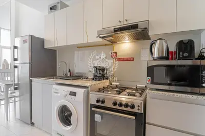 a kitchen with a stove and a washing machine at Royalton - Cozy Studio with Burj Khalifa & Canal Views in Dubai