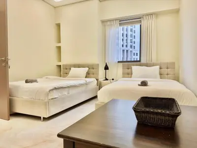 a bedroom with two beds and a table and a window at Renovated 2bdr in Sadaf 7 JBR in Dubai
