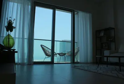 a living room with a large glass door with a chair at Next to Burj Khalifa 5 Mins Walk To Dubai Mall in Dubai