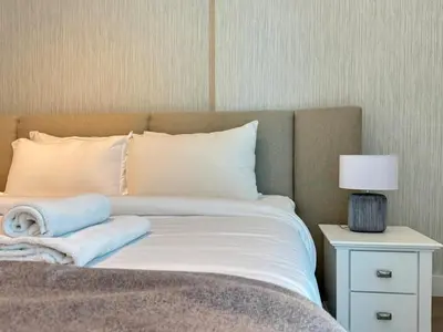 a bed with white sheets and a nightstand with a lamp at DAYF-POLO Modern 1BR Escape Polo Residences Meydan in Dubai