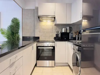 a kitchen with white cabinets and a stainless steel oven at DAYF-POLO Modern 1BR Escape Polo Residences Meydan in Dubai