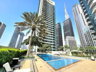 a palm tree and a swimming pool in a city at Luxury Apt Near Burj & Metro in Dubai