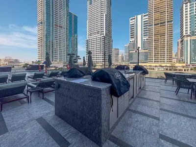 a rooftop patio with tables and chairs and buildings at Frank Poretr - MBL Royal, Jumeirah Lakes Towers in Dubai