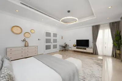 a white bedroom with a bed and a flat screen tv at Maison Privee - Ultra-Luxury Villa with Private Pool & Beach on Palm in Dubai