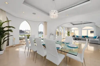 a white dining room with a glass table and white chairs at Maison Privee - Ultra-Luxury Villa with Private Pool & Beach on Palm in Dubai