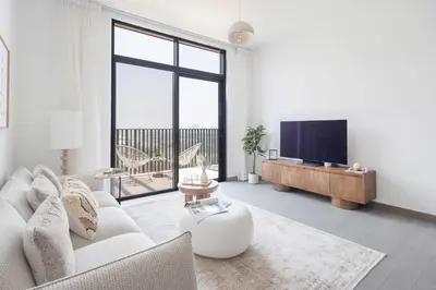 a living room with a white couch and a tv at Frank Porter - Kensington Waters, Sobha Hartland in Dubai