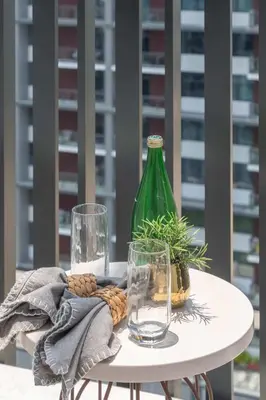 a table with a green bottle and glasses on it at Frank Porter - Kensington Waters, Sobha Hartland in Dubai