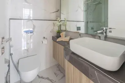 a white bathroom with a sink and a mirror at Frank Poretr - The Pinnacle, Dubai Hills in Dubai