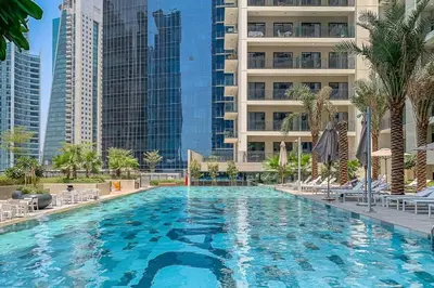 a large swimming pool with palm trees and buildings at Frank Porter - Zada Tower in Dubai