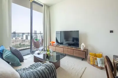 a living room with a tv and a large window at Frank Porter - Binghatti Tulip in Dubai