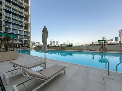 a swimming pool with a lounge chair and an umbrella at Frank Porter - Binghatti Amber in Dubai
