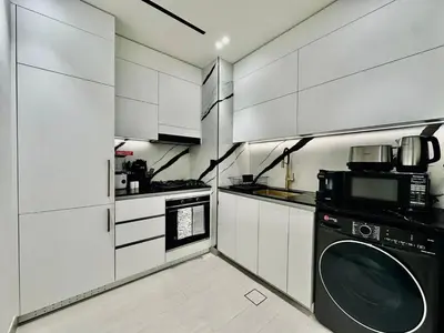 a kitchen with white cabinets and a washing machine at Artful Canal Escape With Jacuzzi And City Views! in Dubai