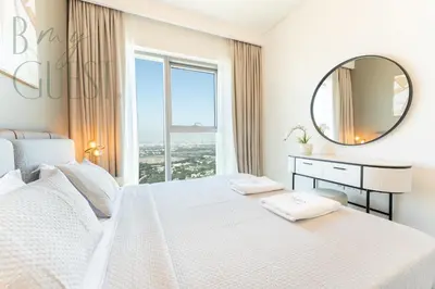 a white bedroom with a large window and a mirror at Spice of Sophistication in a 2BR Downtown Views II in Dubai