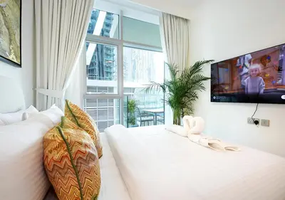 a white bedroom with a large window and a tv at Urban Oasis 2BR Retreat in Dubai with Pool View in Dubai