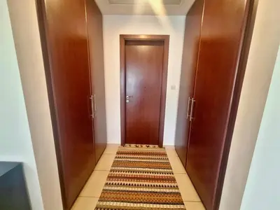 a hallway with a wooden door and a rug at Tratoli JBR Shared Hostel with Sea View in Dubai