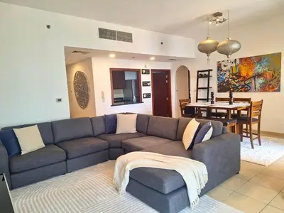 a living room with a couch and a dining room at Tratoli JBR Shared Hostel with Sea View in Dubai