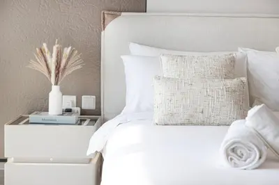 a bed with white sheets and pillows and a side table at LUXE Rooftop Infinity Pool 5 Mins to JBR Dubai Marina View in Dubai
