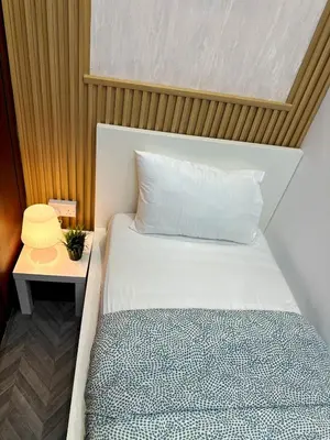 a bed with a white pillow and a side table at Retreat One Room In Tecom Barsha Heights in Dubai