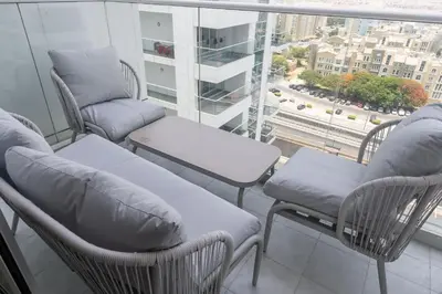 a balcony with chairs and a couch and a window at StayShort - Beautiful Al Furjan 2 bed apartment for 4 people in Dubai