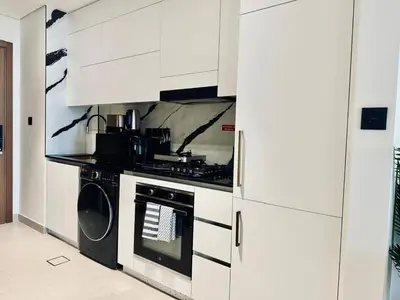 a kitchen with a stove and white cabinets at Luxe Studio Retreat Jacuzzi Parking, Pool & Gym in Dubai