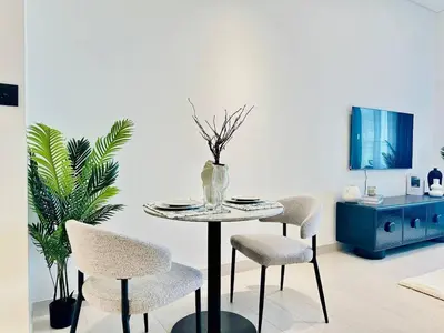 a table and chairs in a living room with a tv at Luxe Studio Retreat Jacuzzi Parking, Pool & Gym in Dubai