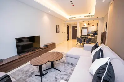 a living room with a white couch and a tv at Elegant 2BR Apt Nobles Tower with Pool and Gym in Dubai